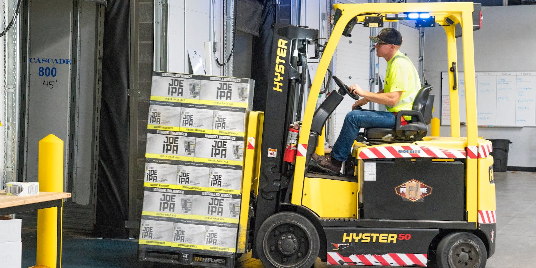 pexels-photo-1267324 man riding a yellow forklift lifting boxes